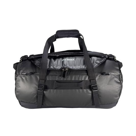 Front view of 65 litre Tatonka barrel bag with adjustable, top carry handles, grab handles on all sides, and padded, removable and adjustable backpack shoulder straps. Main compartment top opening has 2-way lockable zip sliders, while main body has compression straps and a padded bottom - Black | Ships from Melbourne