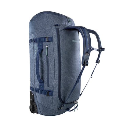 Back three-quarter view of 105 litre Tatonka Duffel Roller with side zip pocket and compression straps, stowaway shoulder straps, grab handles on top and side, large zip opening for main compartment with lockable zip slider. Shown with stowaway shoulder straps deployed - Navy